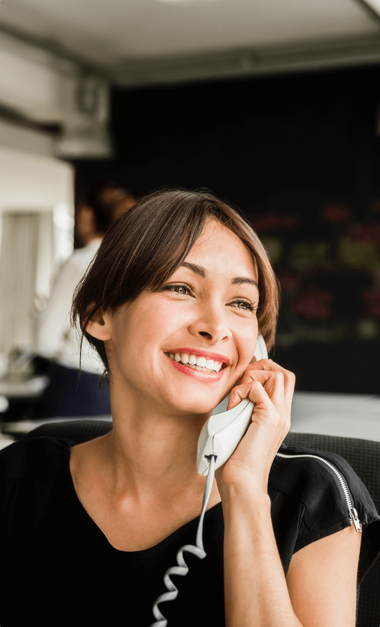 Cheerful businesswoman using telephone in office