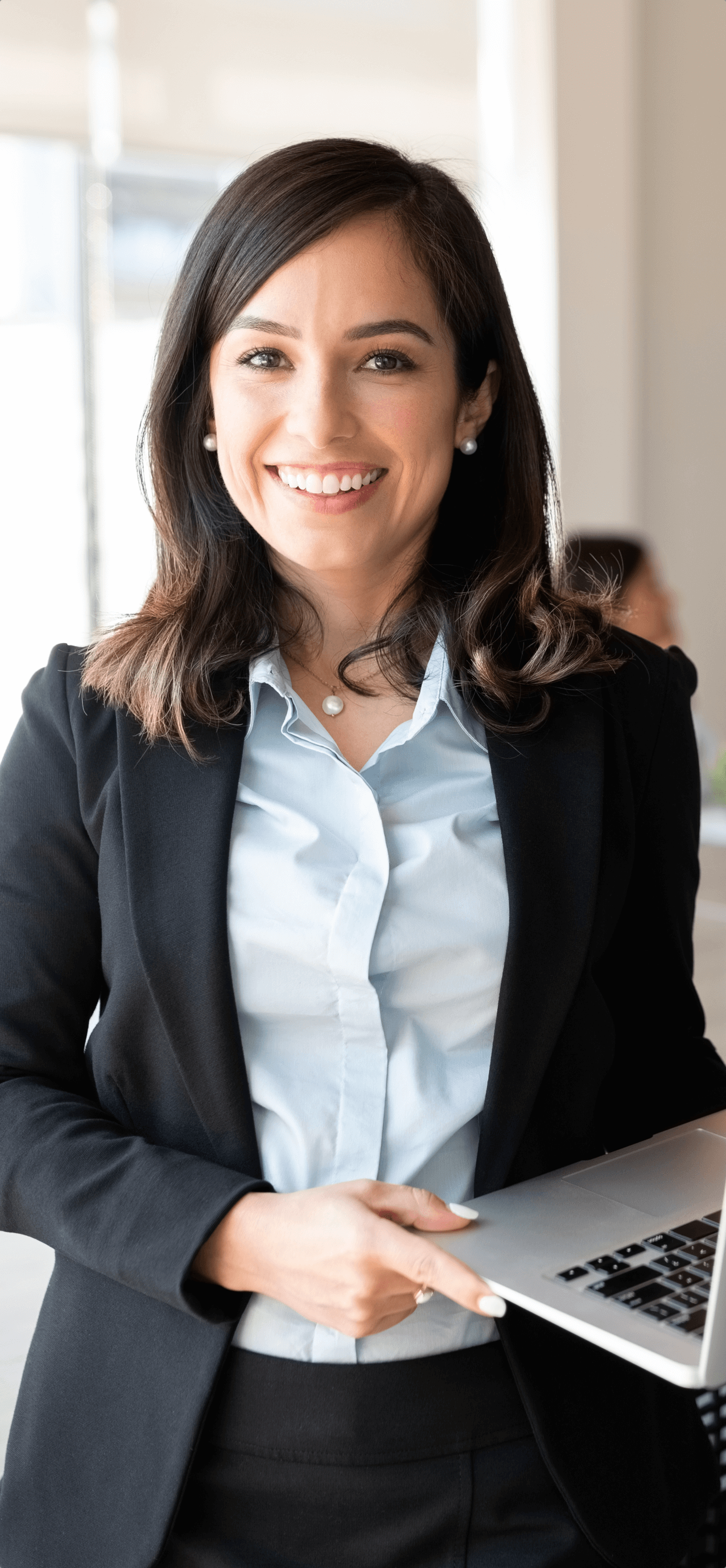 Portrait of smiling female entrepreneur holding a laptop with team in background at office conference room