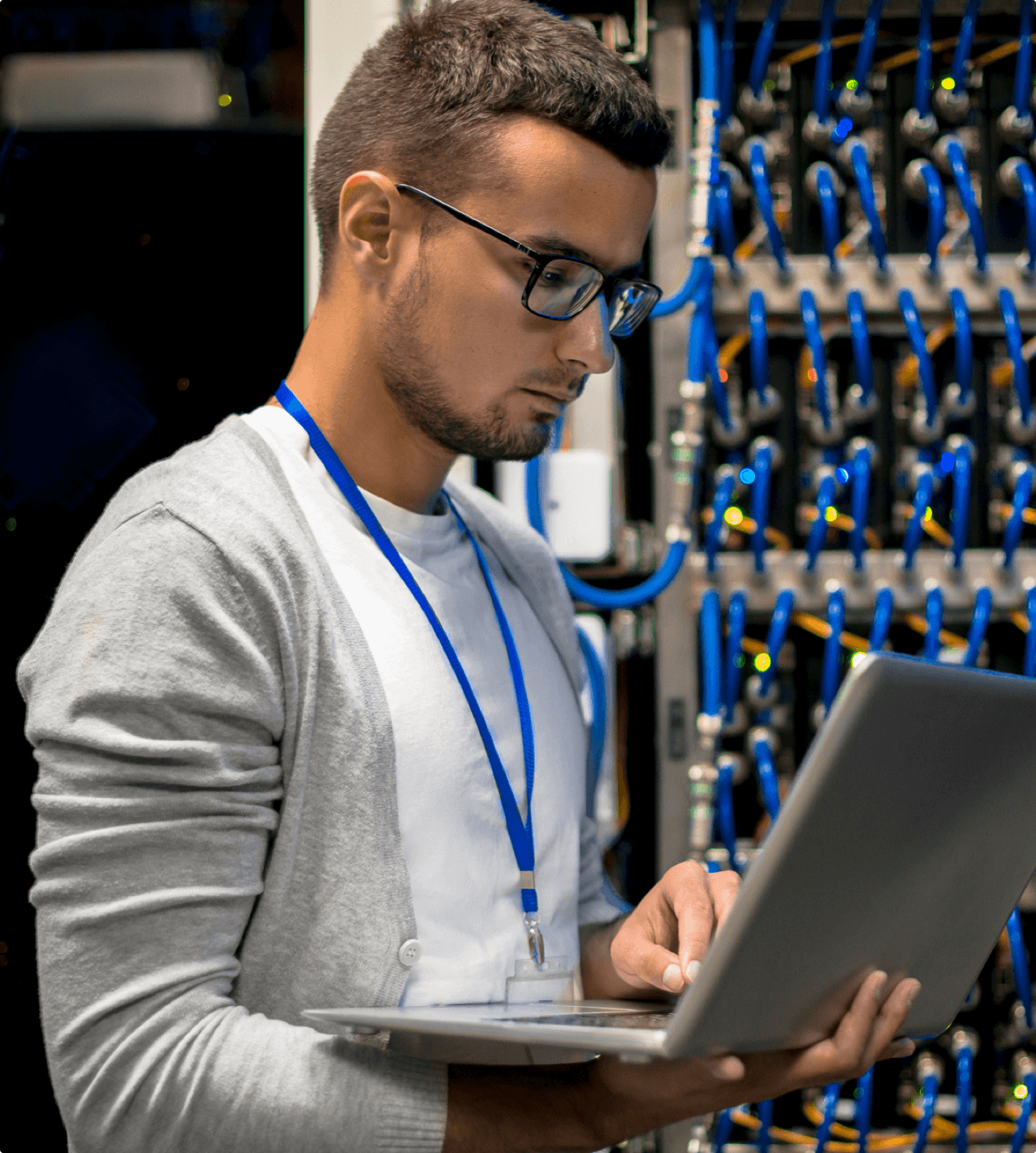 Side view portrait of young man with laptop standing by server cabinet while working with supercomputer